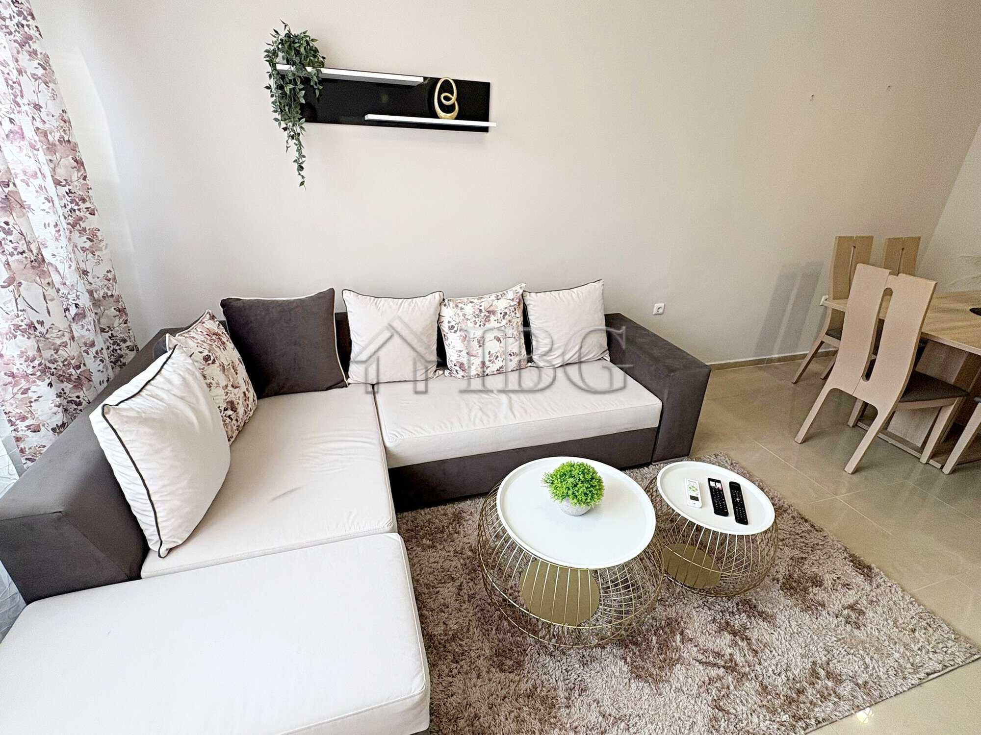 Bright living room with a sectional sofa, decorative cushions, and a cozy rug in a sunny apartment.
