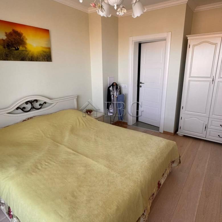 Bright bedroom featuring a chandelier and a double bed with a green bedspread in Sveti Vlas.