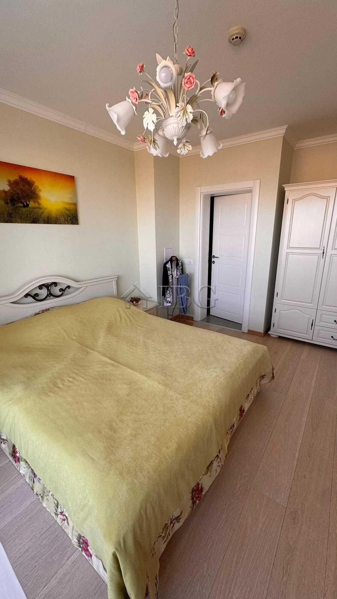 Bright bedroom featuring a chandelier and a double bed with a green bedspread in Sveti Vlas.