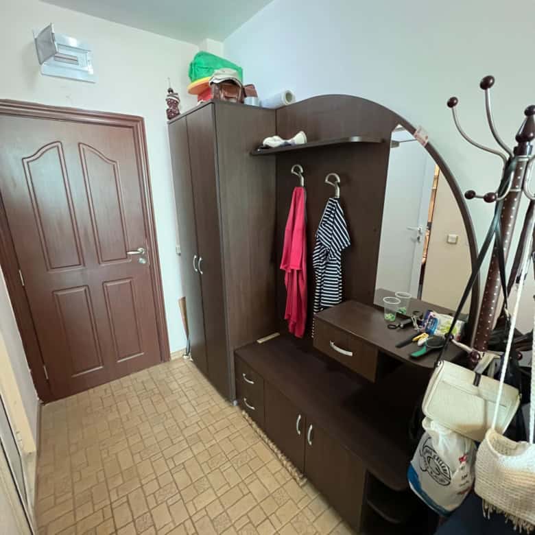 Interior view of a small entryway with wardrobe, coat hooks, and accessories in a one-bedroom maison.