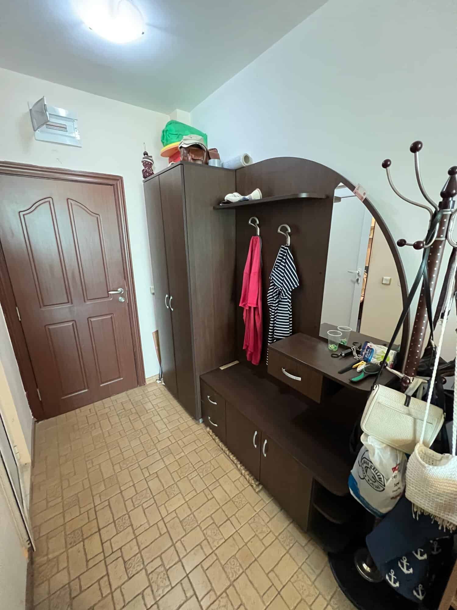 Interior view of a small entryway with wardrobe, coat hooks, and accessories in a one-bedroom maison.