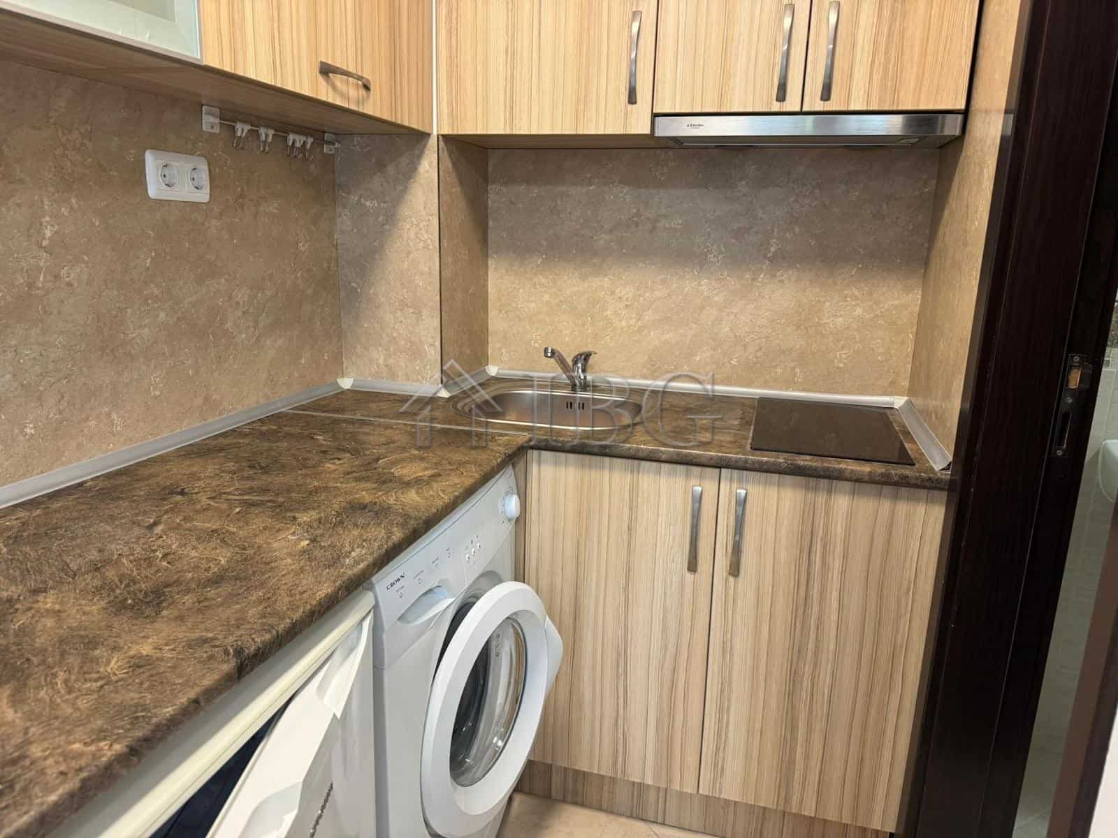 Compact kitchen with washing machine and wooden cabinets in Cascadas Complex, Sunny Beach.