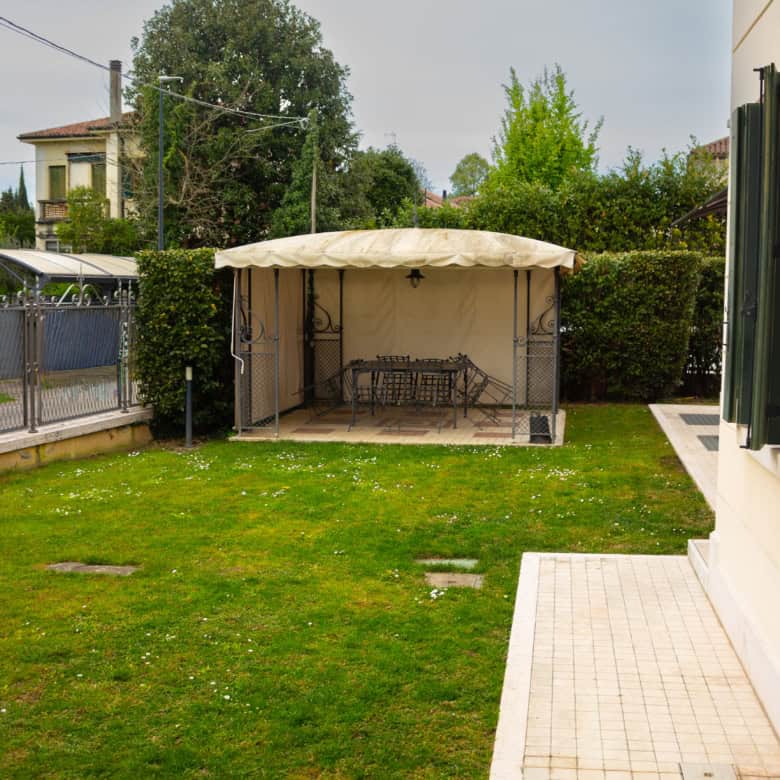 Gazebo with seating area in a well-maintained garden.