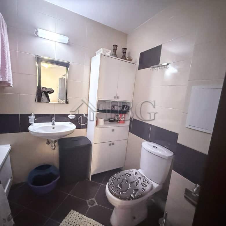 Bright, clean bathroom with white fixtures, a mirror, and storage cabinet.