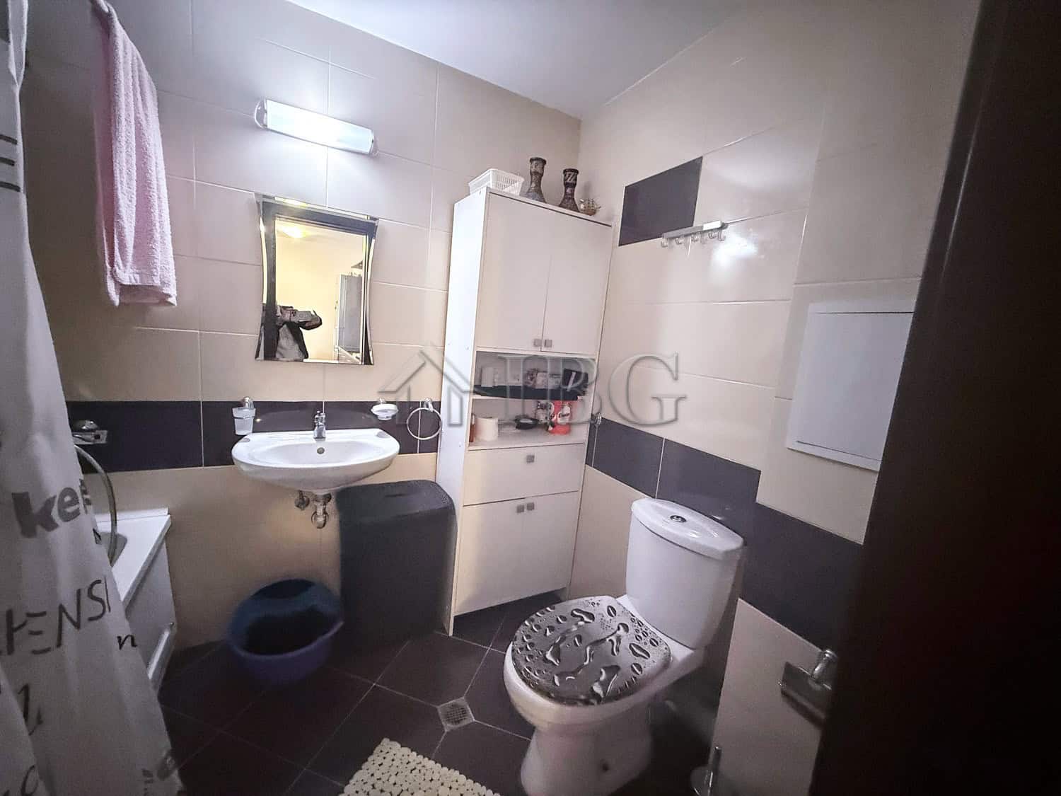 Bright, clean bathroom with white fixtures, a mirror, and storage cabinet.