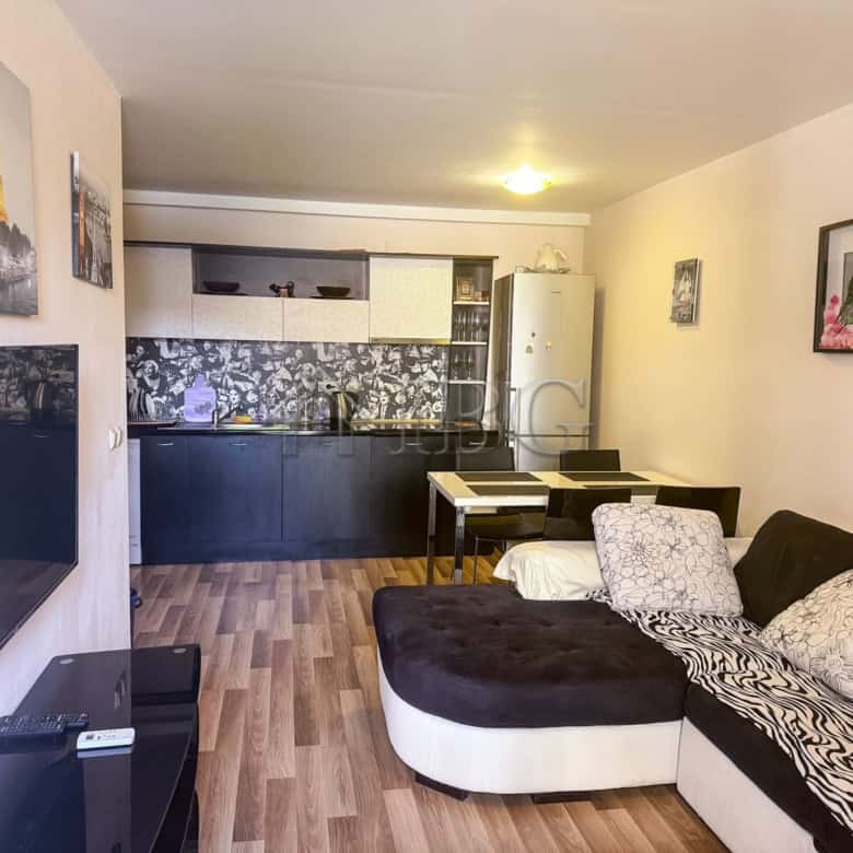 Spacious living room with sofa and artwork, open-plan kitchen area, ideal for comfortable seaside li.