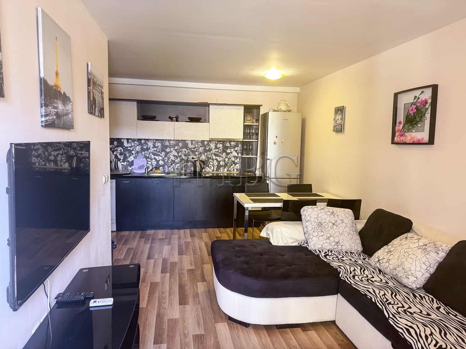 Spacious living room with sofa and artwork, open-plan kitchen area, ideal for comfortable seaside li.