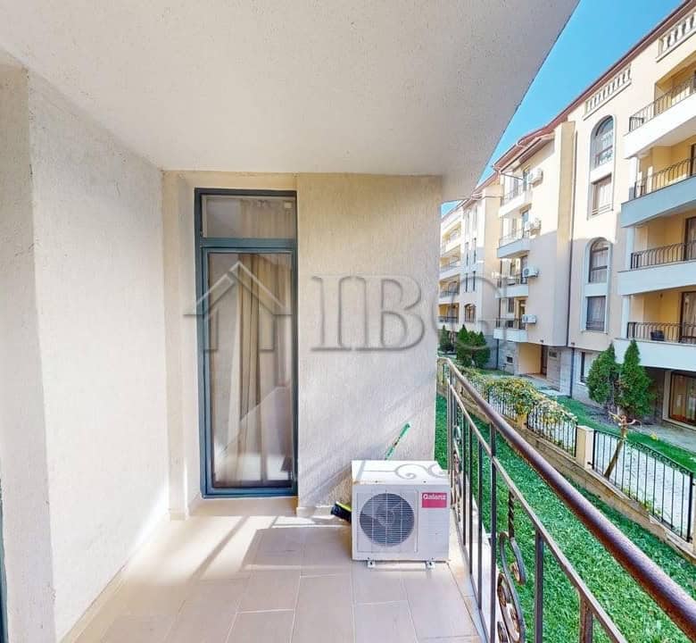 Balcony view of a one-bedroom apartment in Sunny Beach with neighboring buildings and greenery.