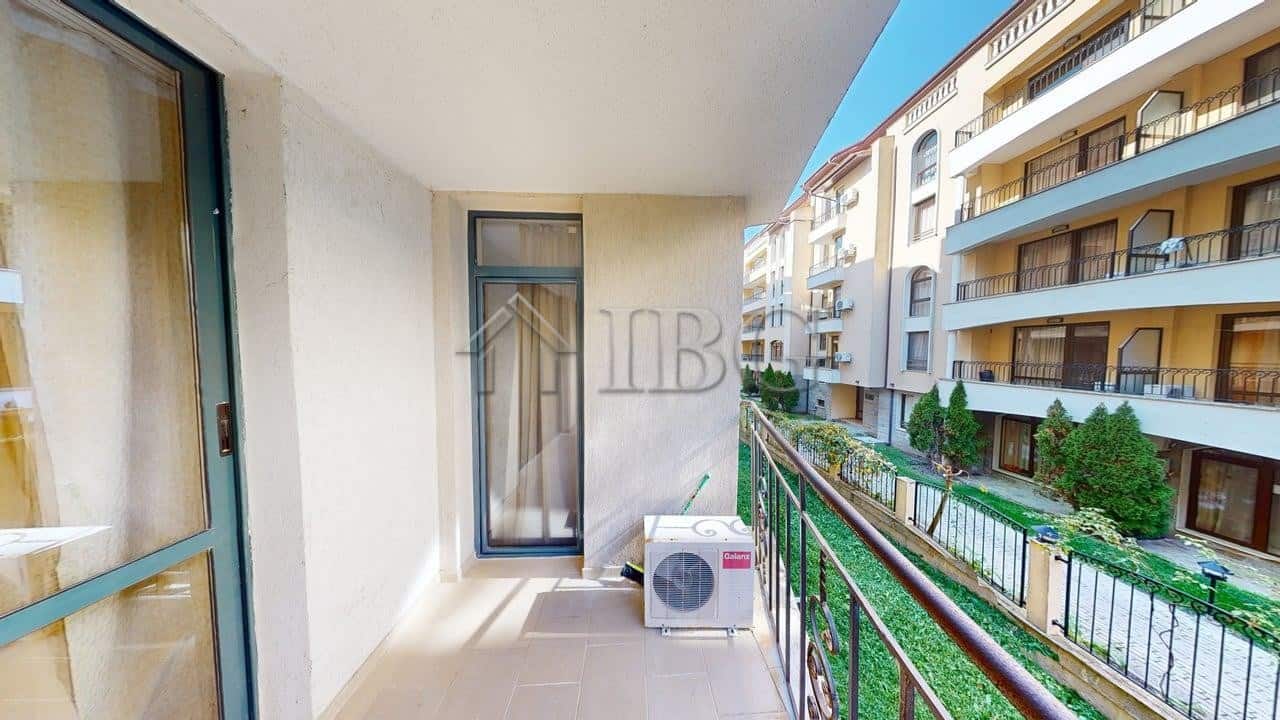 Balcony view of a one-bedroom apartment in Sunny Beach with neighboring buildings and greenery.