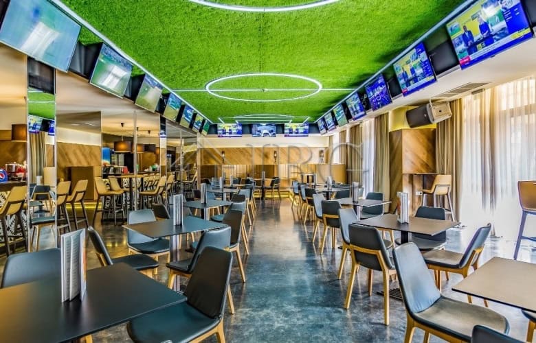 Luxurious hotel lounge featuring multiple TV screens, contemporary furniture, and a vibrant atmosphe.