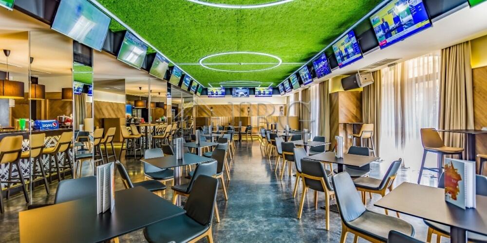 Luxurious hotel lounge featuring multiple TV screens, contemporary furniture, and a vibrant atmosphe.