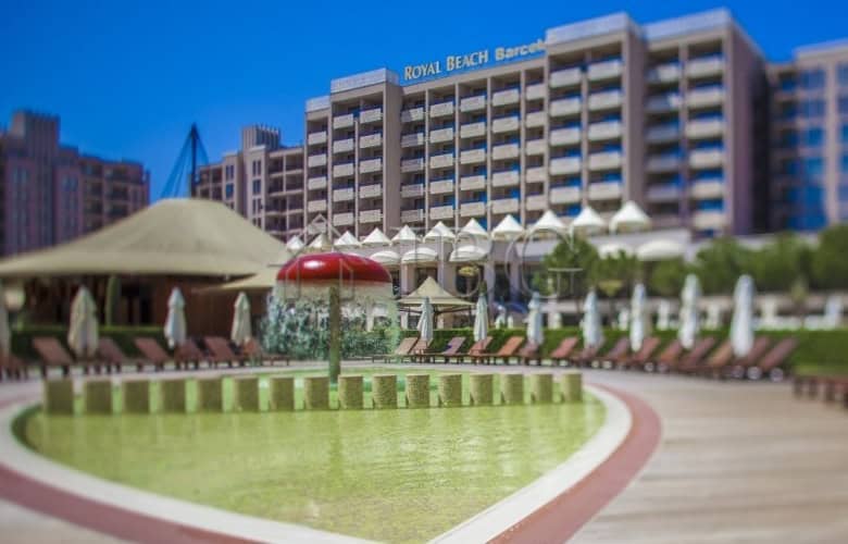 Pool area with sun loungers and umbrellas at Barceló Royal Beach hotel, overlooking the sea.