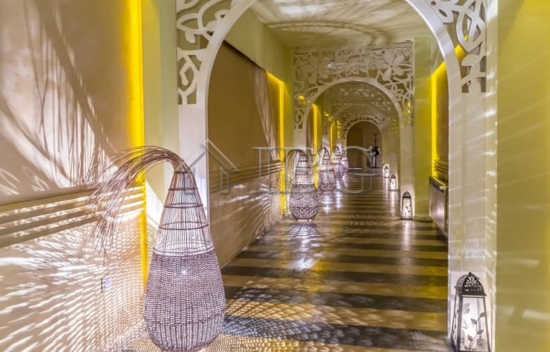 Bright hallway leading to studio with elegant decor and ambient lighting at Royal Beach Barceló.
