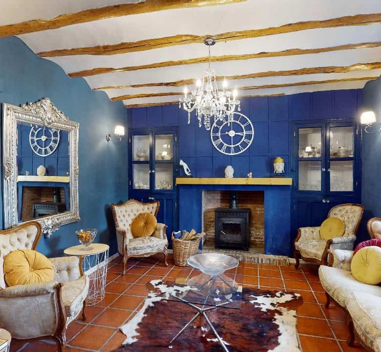 Charming boutique hotel living room with vibrant blue walls, elegant furniture, and rustic wooden ce.