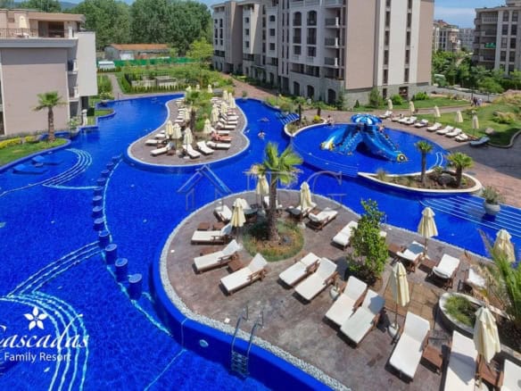 Luxurious swimming pool at Cascadas Family Resort with sun loungers and tropical landscaping.