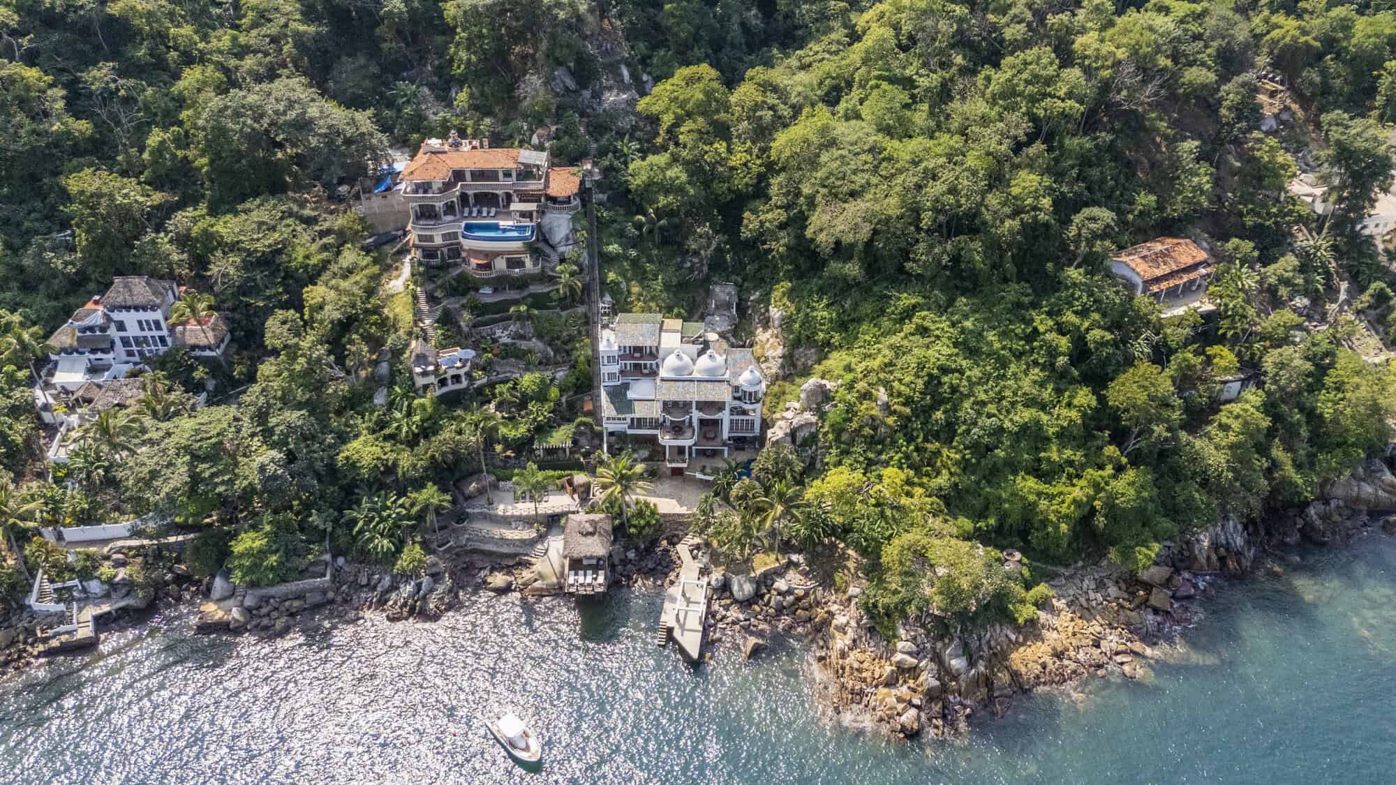 Luxury waterfront homes on a lush green coastline.
