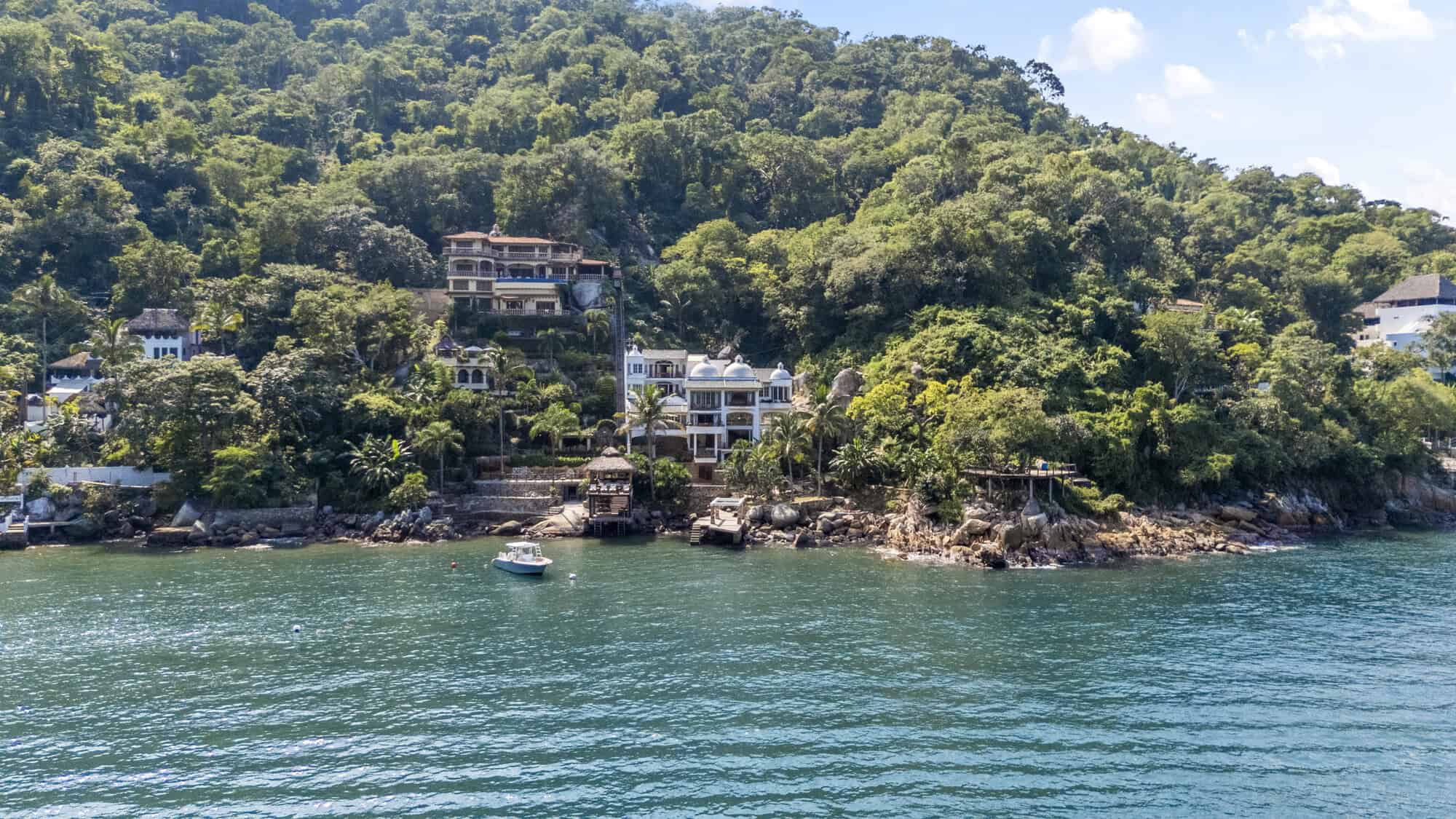 Seaside homes nestled on lush green hills overlooking the water.