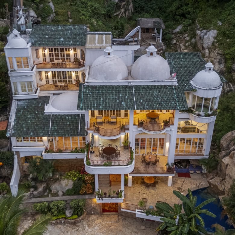 Elegant hillside villa overlooking the ocean with lush greenery and modern amenities.