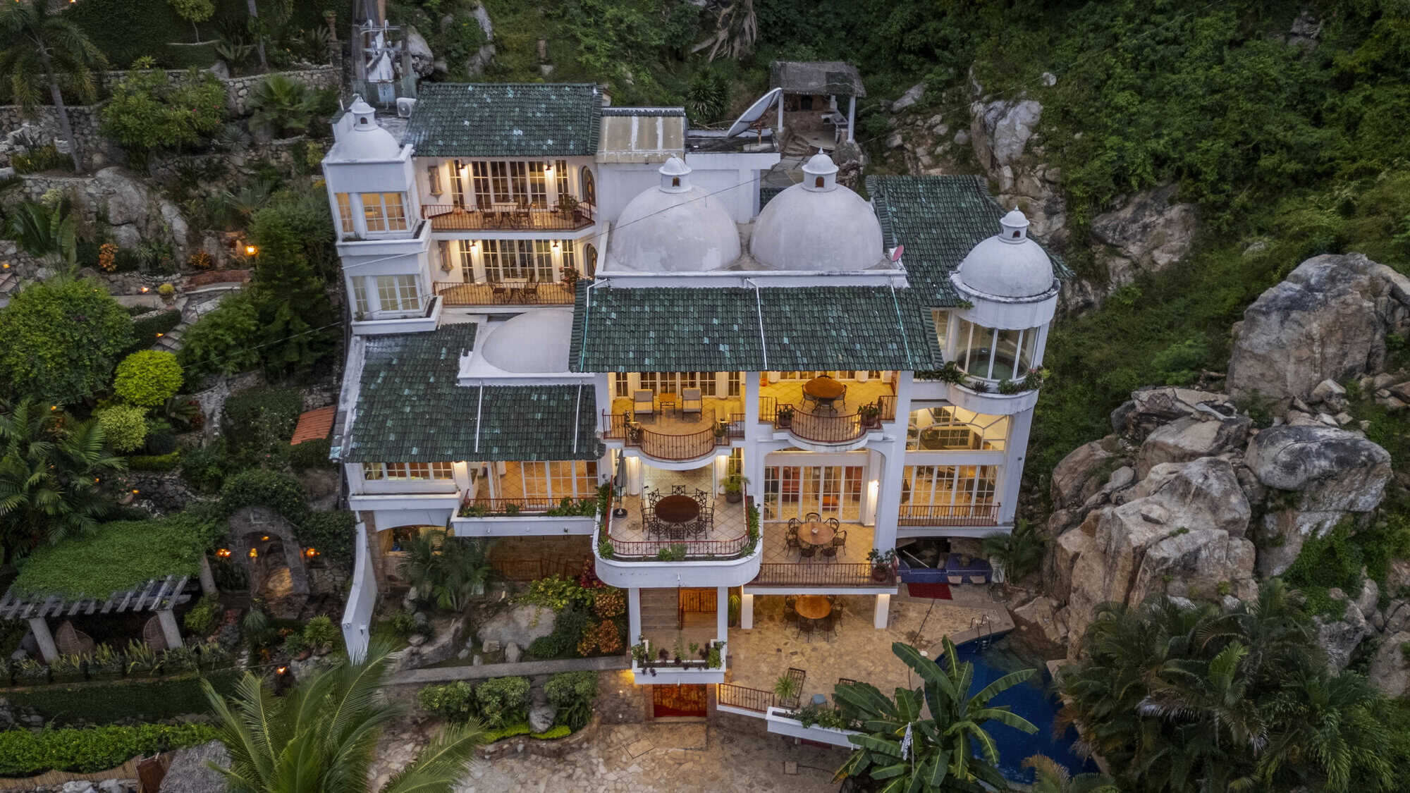Elegant hillside villa overlooking the ocean with lush greenery and modern amenities.