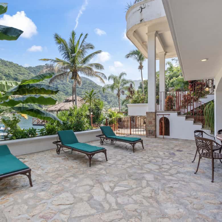 Luxury villa terrace with tropical garden and mountain view, featuring sun loungers and outdoor dini.