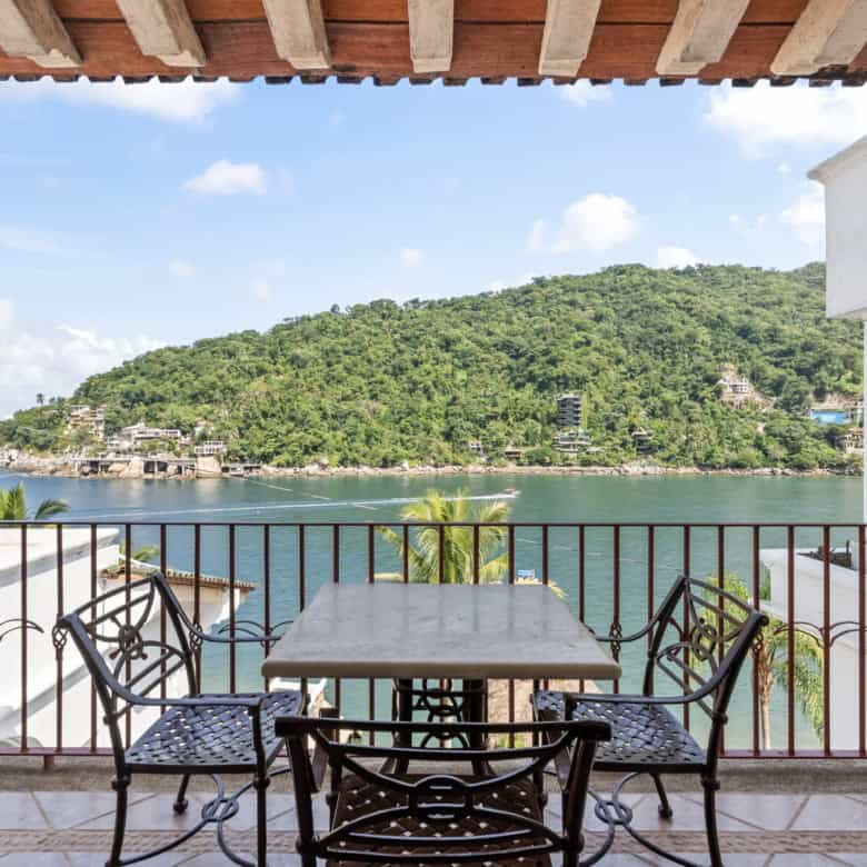Beachfront balcony with ocean view and lush green island.