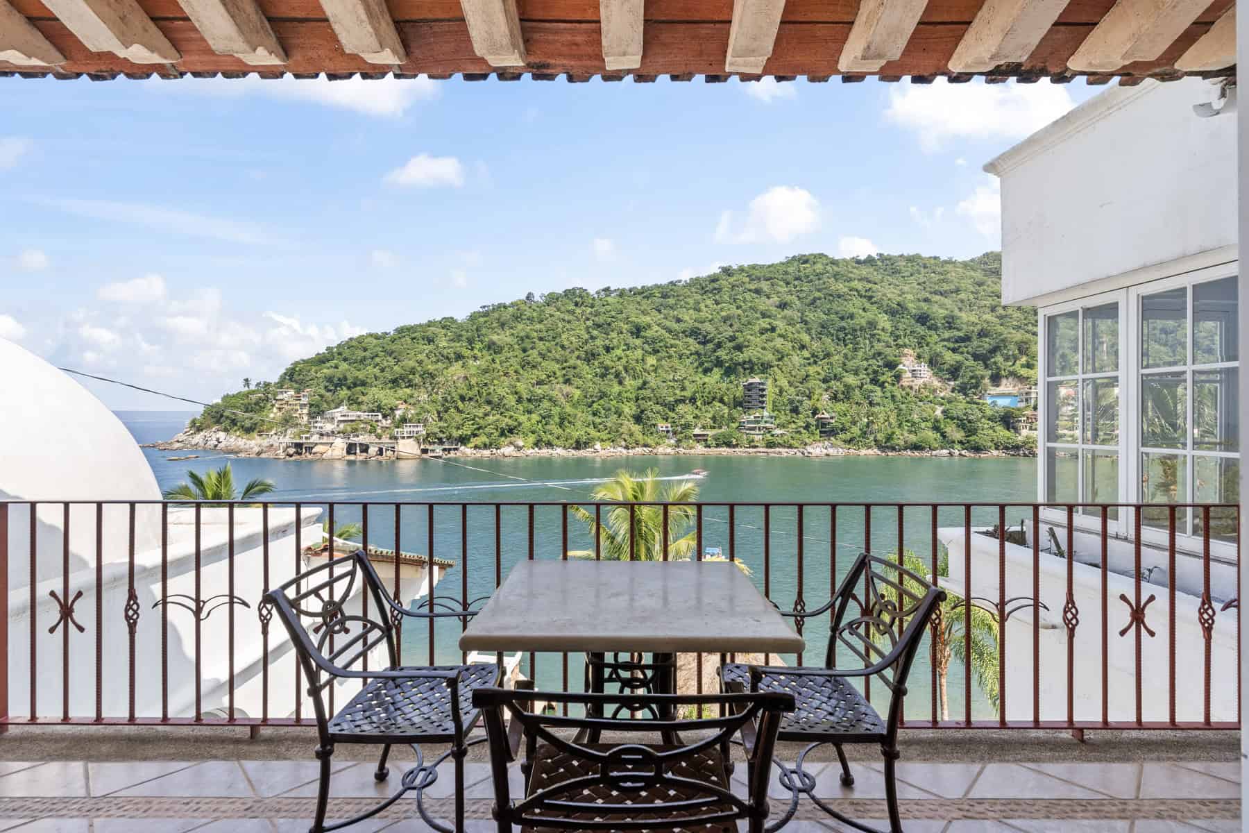 Beachfront balcony with ocean view and lush green island.