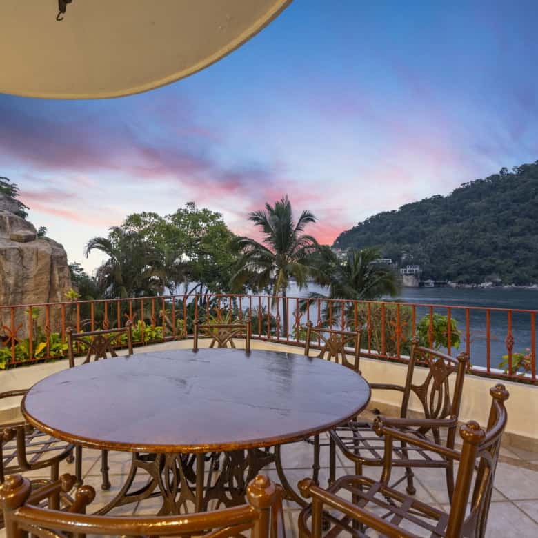 Outdoor dining balcony overlooking the water and lush hills.