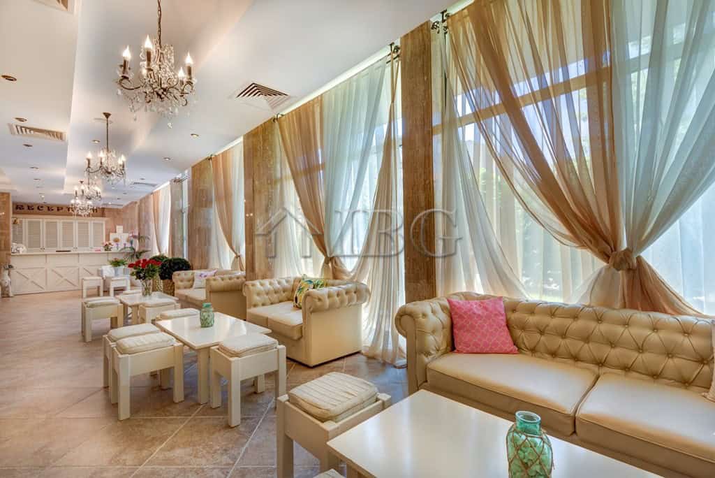 Spacious 1-bedroom apartment living room with elegant furniture and large windows with flowing curta.