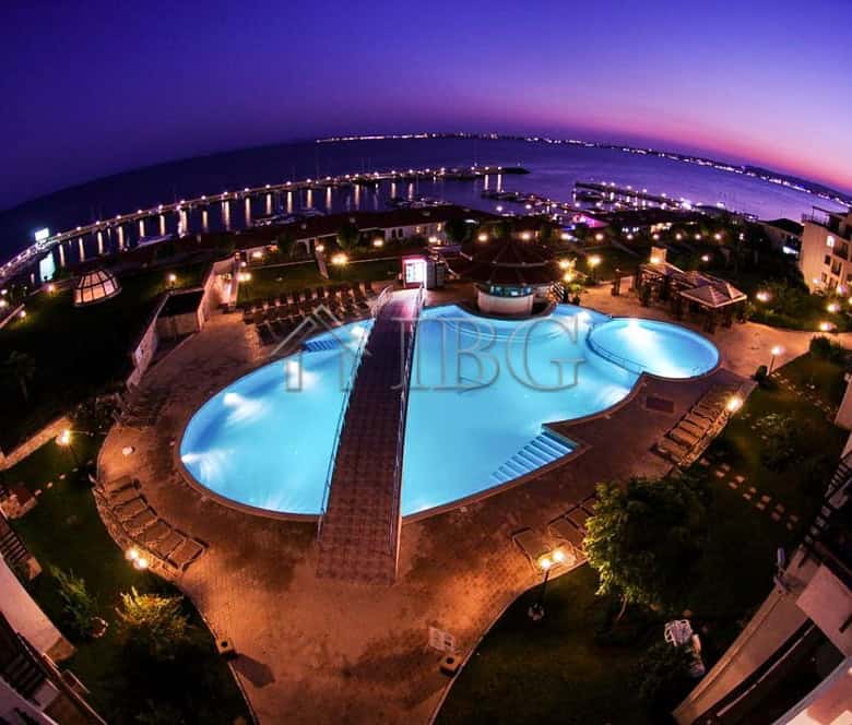 Swimming pool with city and sea views at sunset, illuminated by lights in Sveti Vlas.