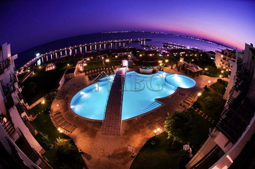Swimming pool with city and sea views at sunset, illuminated by lights in Sveti Vlas.