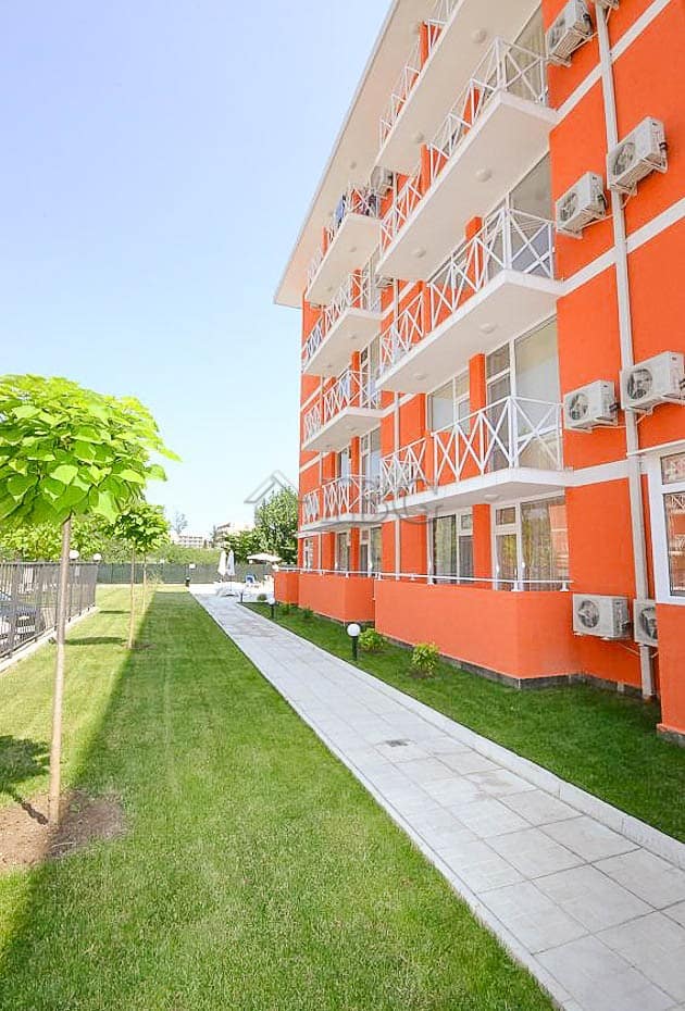 Bright orange modern apartment building with balconies in Sunny Beach, Bulgaria.