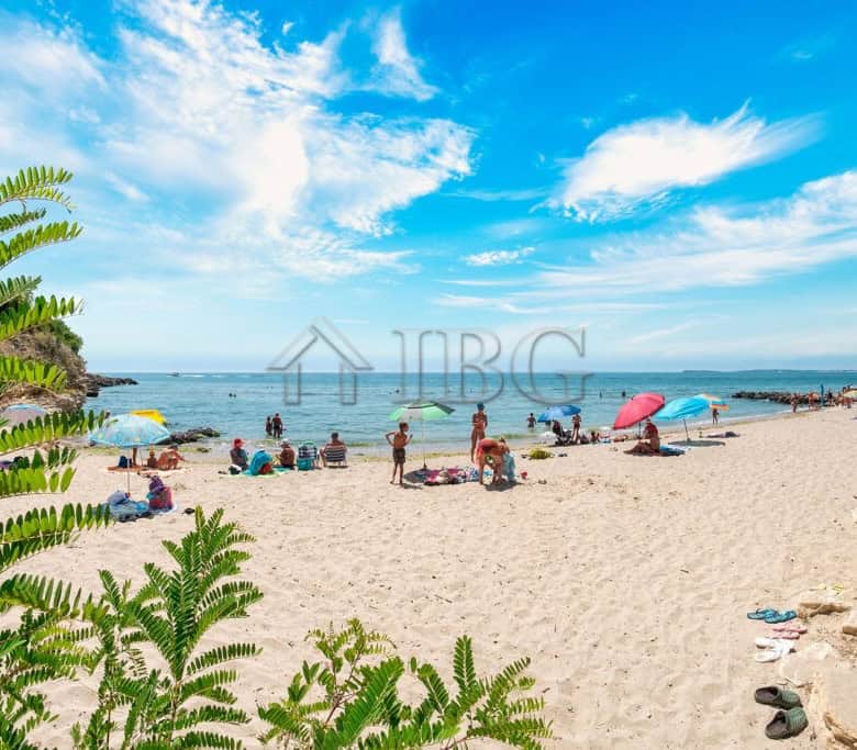 Beach view of Sveti Vlas with sunbathers and umbrellas on the sandy shore.