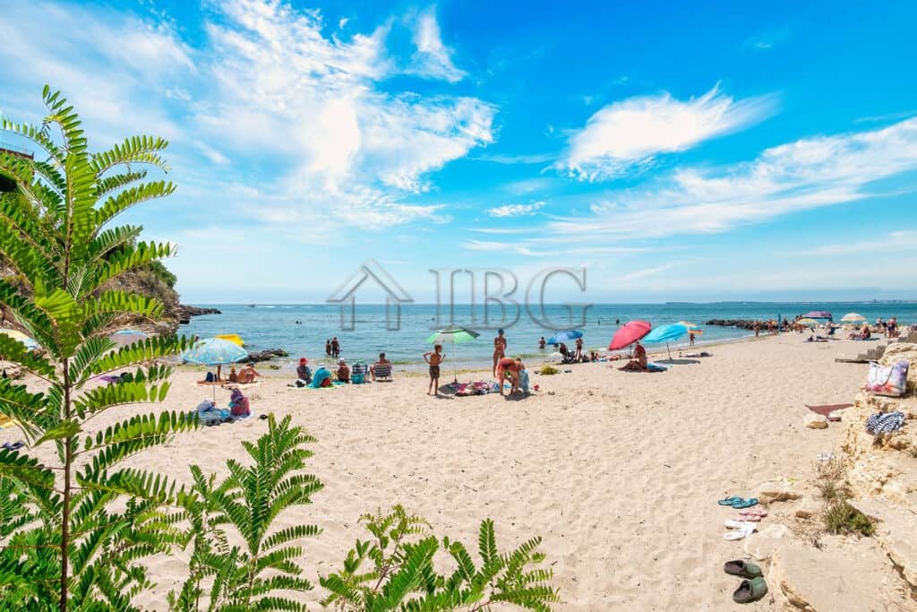 Beach view of Sveti Vlas with sunbathers and umbrellas on the sandy shore.