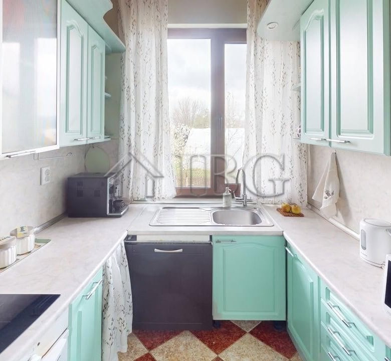 Bright kitchen with mint green cabinets and large window in Poroy Village home.