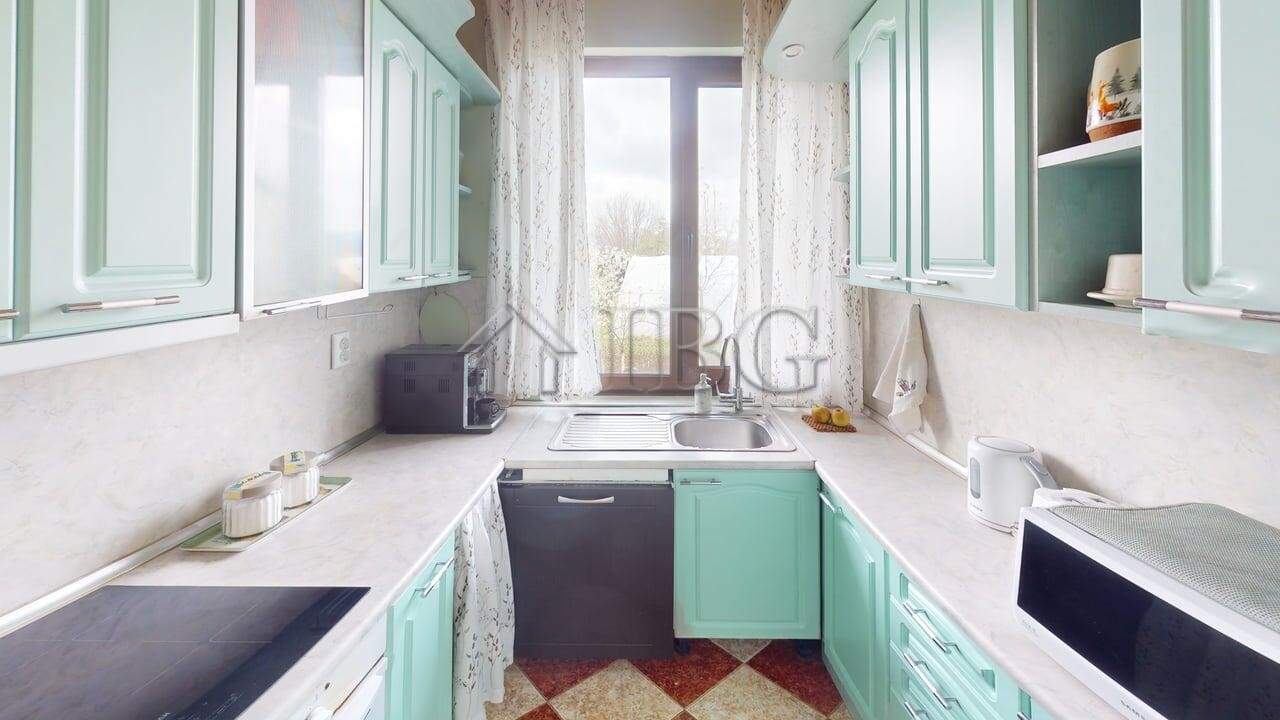 Bright kitchen with mint green cabinets and large window in Poroy Village home.