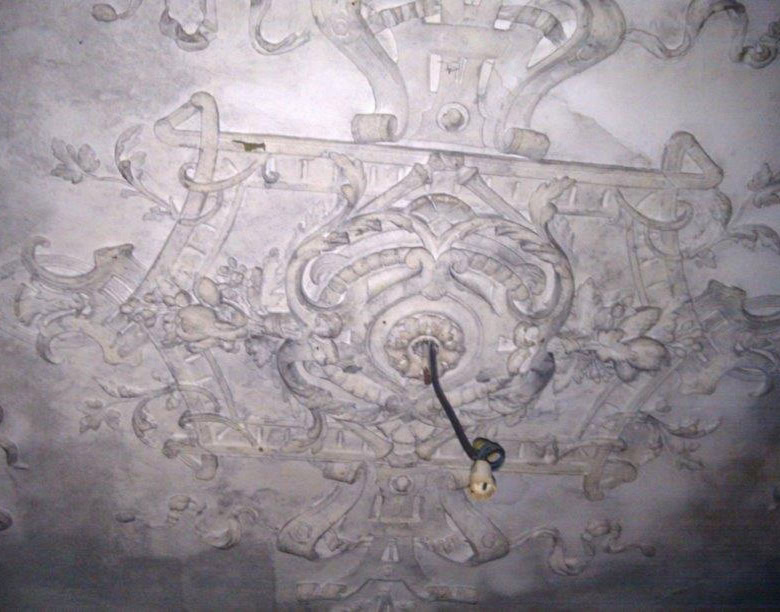 Old ornate ceiling with intricate plasterwork in a historic building.