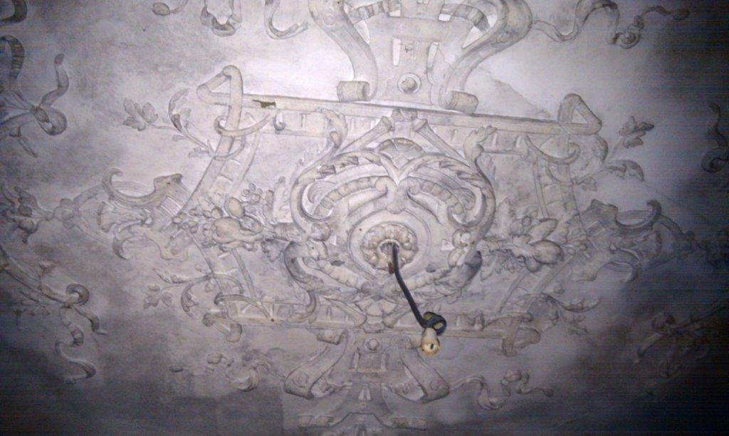 Old ornate ceiling with intricate plasterwork in a historic building.