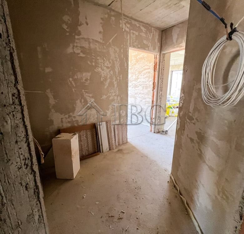 Interior view of a partially finished apartment with construction materials and wiring.