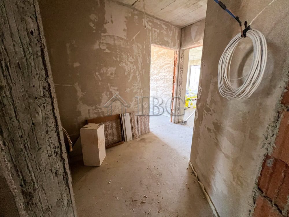 Interior view of a partially finished apartment with construction materials and wiring.