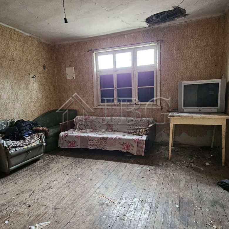 Interior of a house with worn furnishings and a large window in Gyulyovtsa Village.