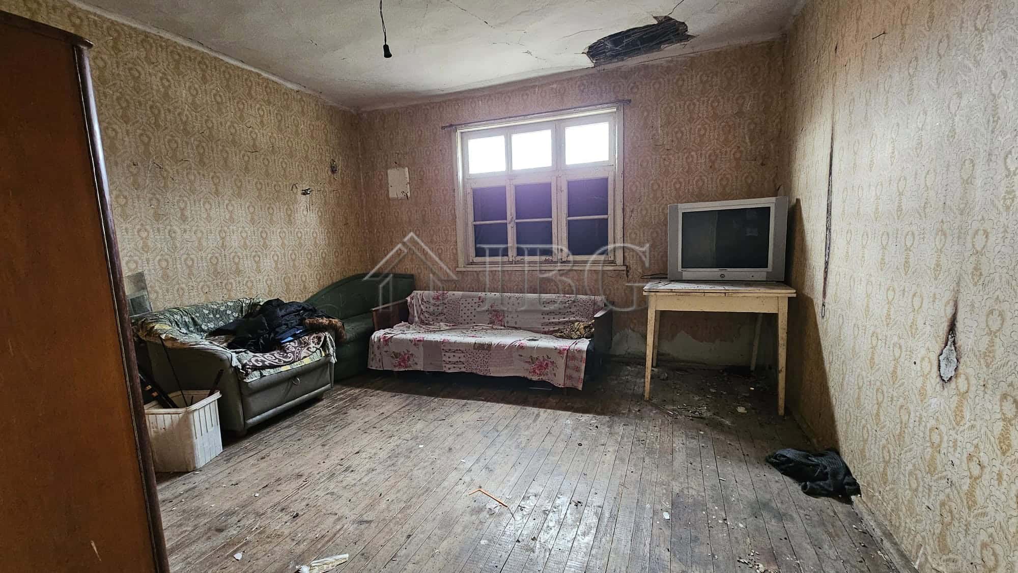 Interior of a house with worn furnishings and a large window in Gyulyovtsa Village.