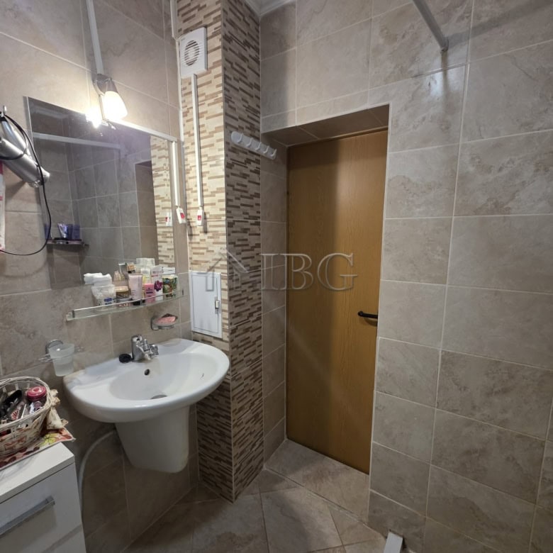 Bright bathroom featuring beige tiles, a mirror, and essential fixtures.