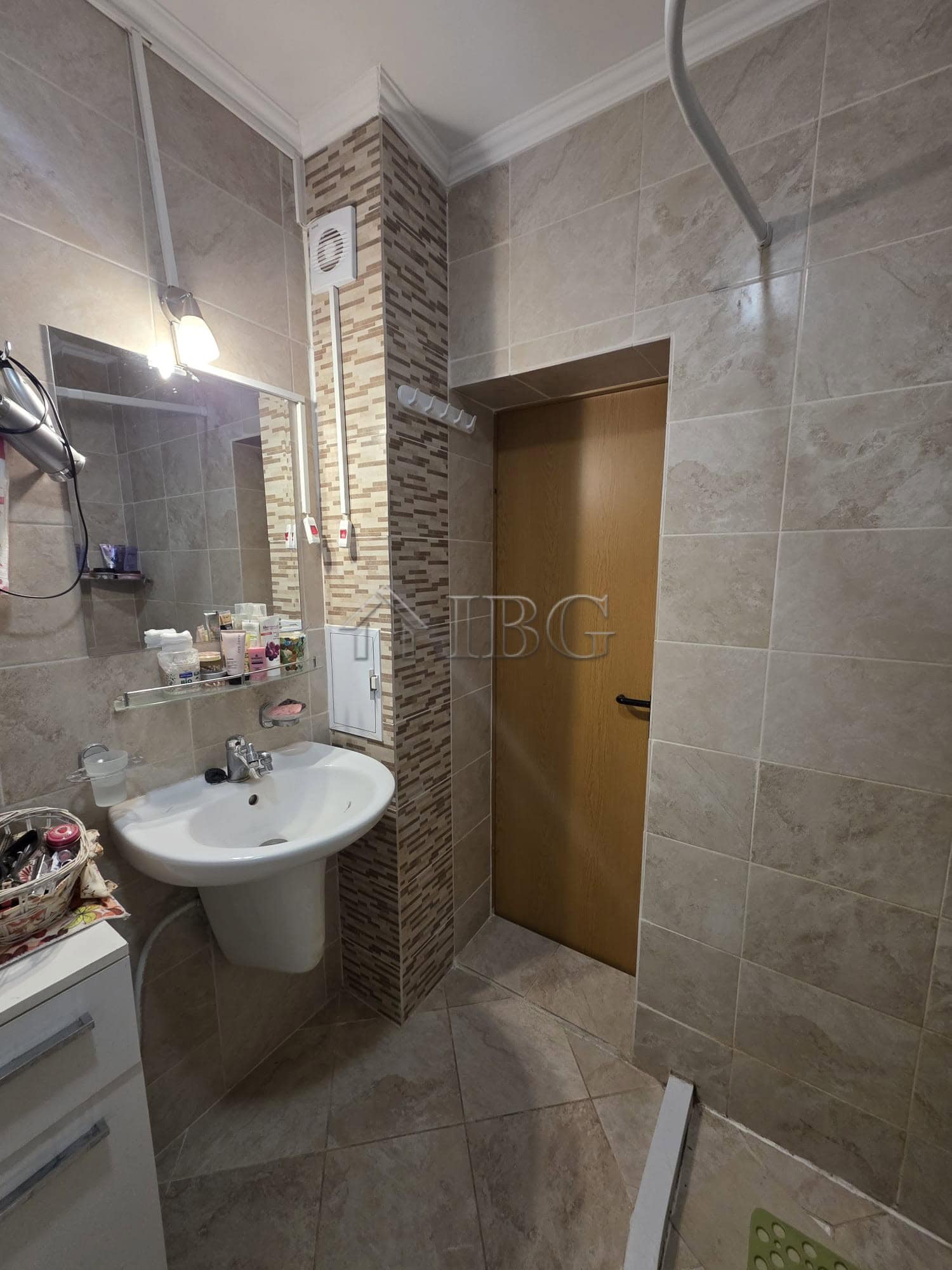 Bright bathroom featuring beige tiles, a mirror, and essential fixtures.