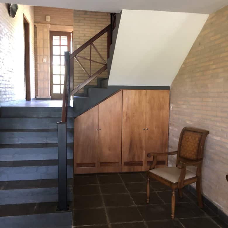 Spacious entryway with staircase and wooden storage cabinets in a cozy Paraguayan home.
