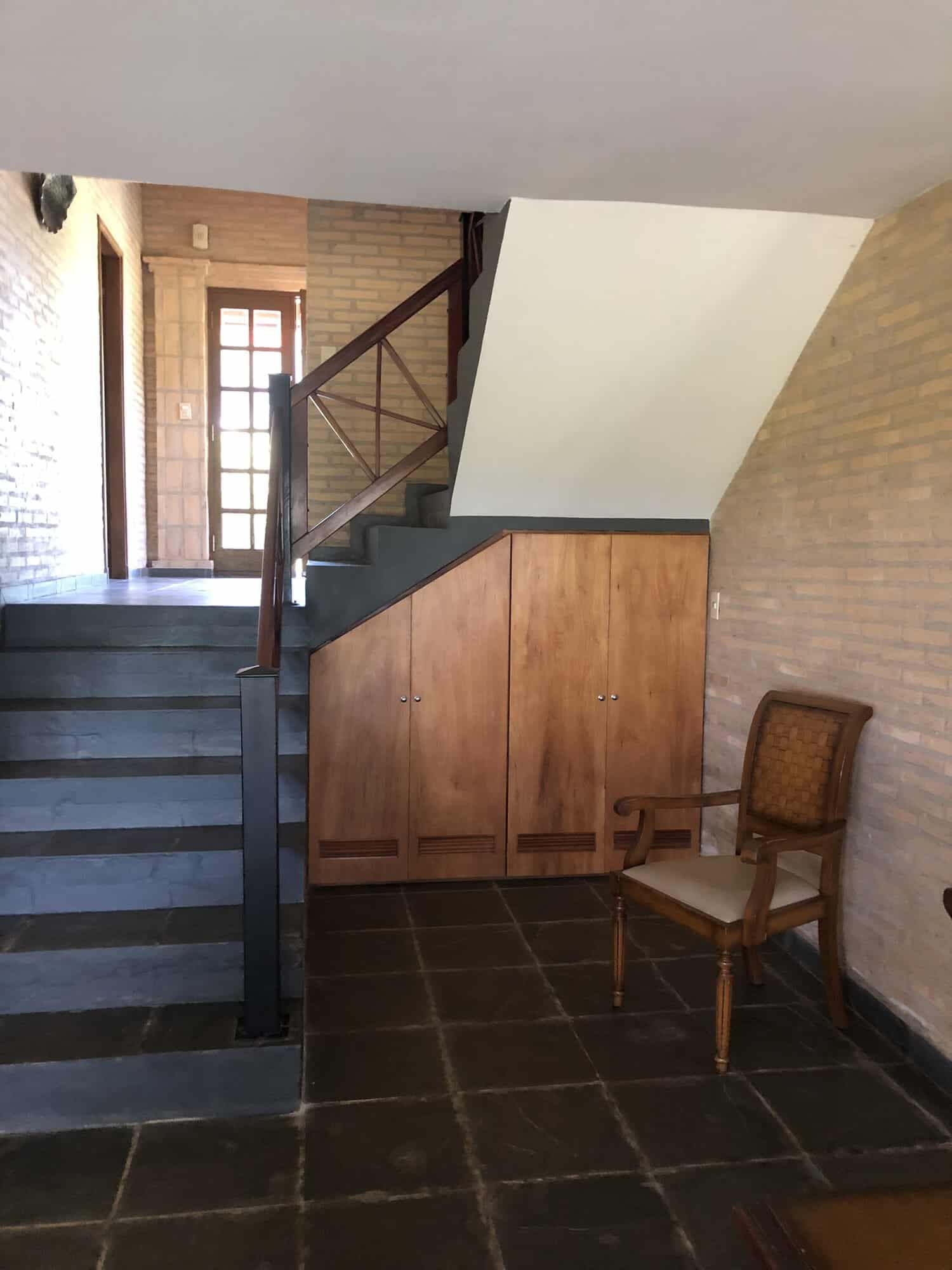 Charming Interior of a 4-Bed House in Paraguay Spacious entryway with staircase and wooden storage cabinets in a cozy Paraguayan home.