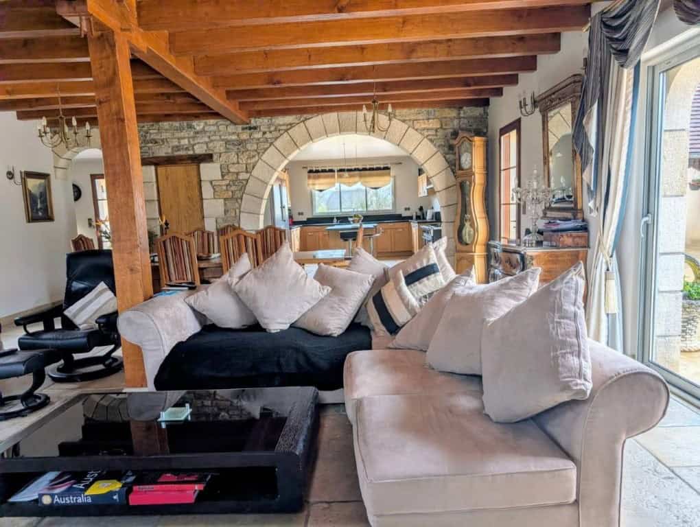 Luxury 4 Bed Le Manoir House in Dordogne Valley Elegant living room with rustic stone walls and wooden beams in Dordogne Valley, France.