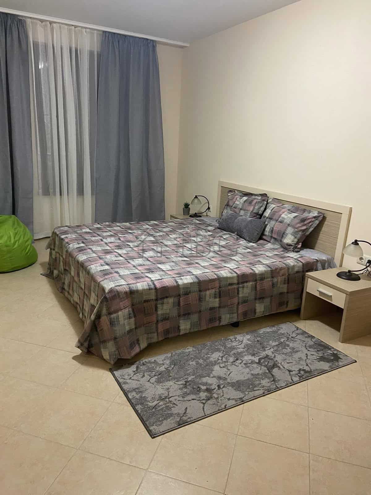 Furnished one-bedroom apartment with bed, nightstands, and curtains in Sunny Beach.
