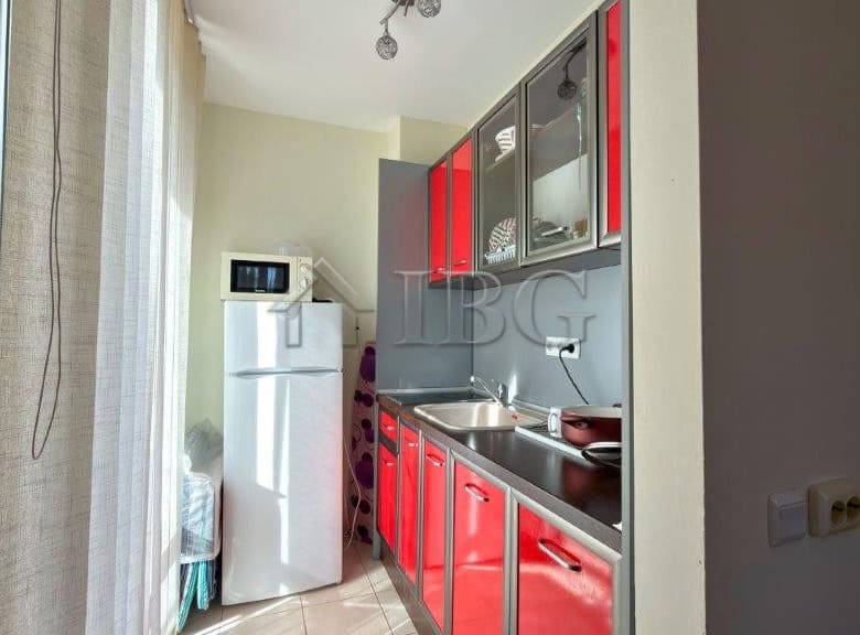 Bright studio kitchen with red cabinets and pool view in Orchid Fort Club, Sunny Beach.