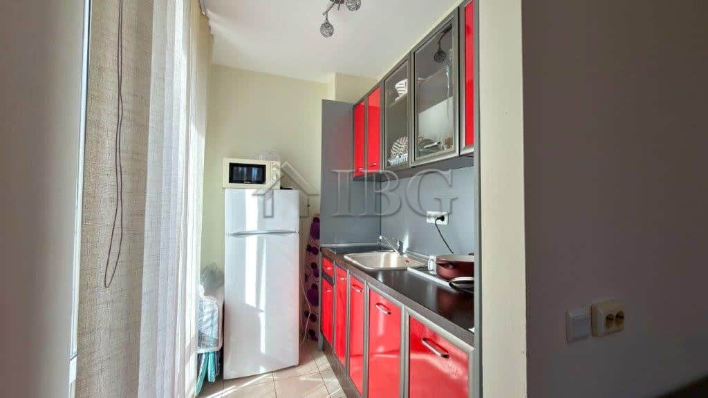 Bright studio kitchen with red cabinets and pool view in Orchid Fort Club, Sunny Beach.