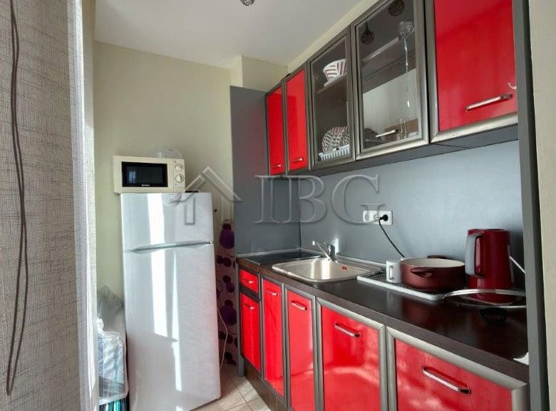 Modern studio kitchen with red cabinets and pool view at Orchid Fort Club, Sunny Beach.